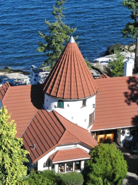 An aerial visual portrays a house with a vibrant red roof tile, hidden among beautiful green grounds