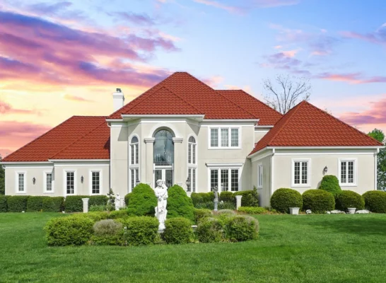 A large white house with a red roof, showcasing the craftsmanship of a roofing tiles manufacturer