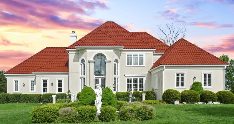 An extravagant spacious residential home with vivid red roofing shingles and verdant grass in front.