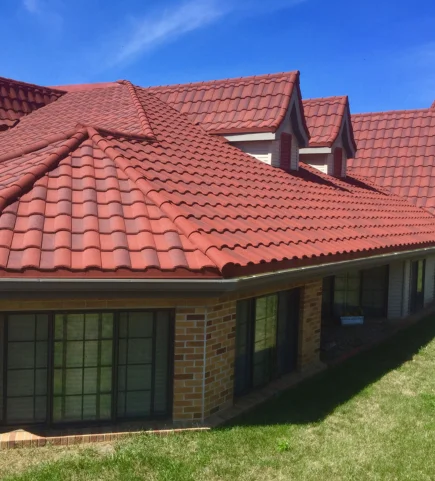 A house with red roofing tiles against a backdrop of clear blue skies has a vivid appearance.